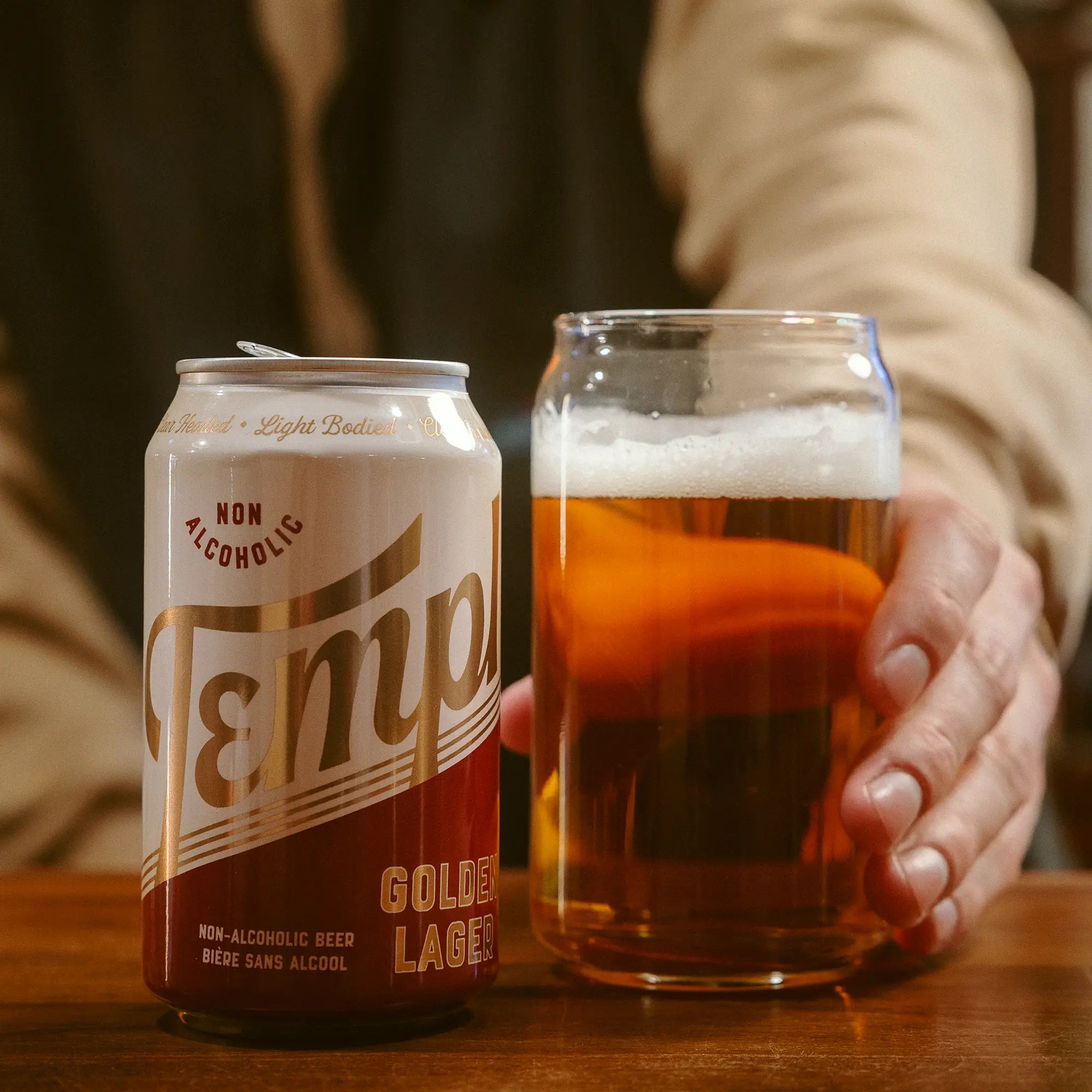 Man offering a can and glass of Templ beer to the viewer